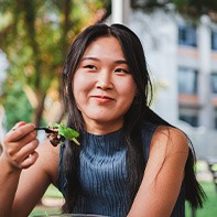 Woman smiling while eating lunch outside