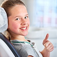 Smiling girl giving thumbs up in dental chair