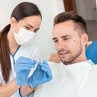 A female dentist showing a male patient what a clear aligner looks like and how to wear it