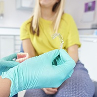 Hand with surgical glove holding Invisalign tray