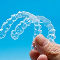closeup of person holding two clear aligners 