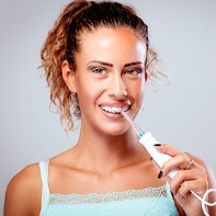 Young woman with braces using water flosser