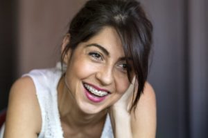 An older woman with braces smiling.