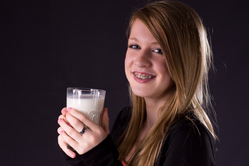 Young girl with braces holding a glass of milk