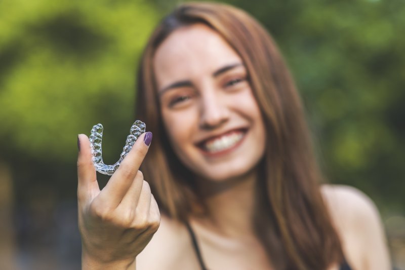 Woman outside holding an Invisalign aligner