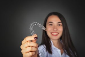 Smiling woman holding clear retainer