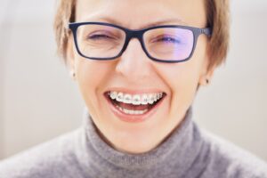 Middle-aged woman with glasses showing braces while smiling.